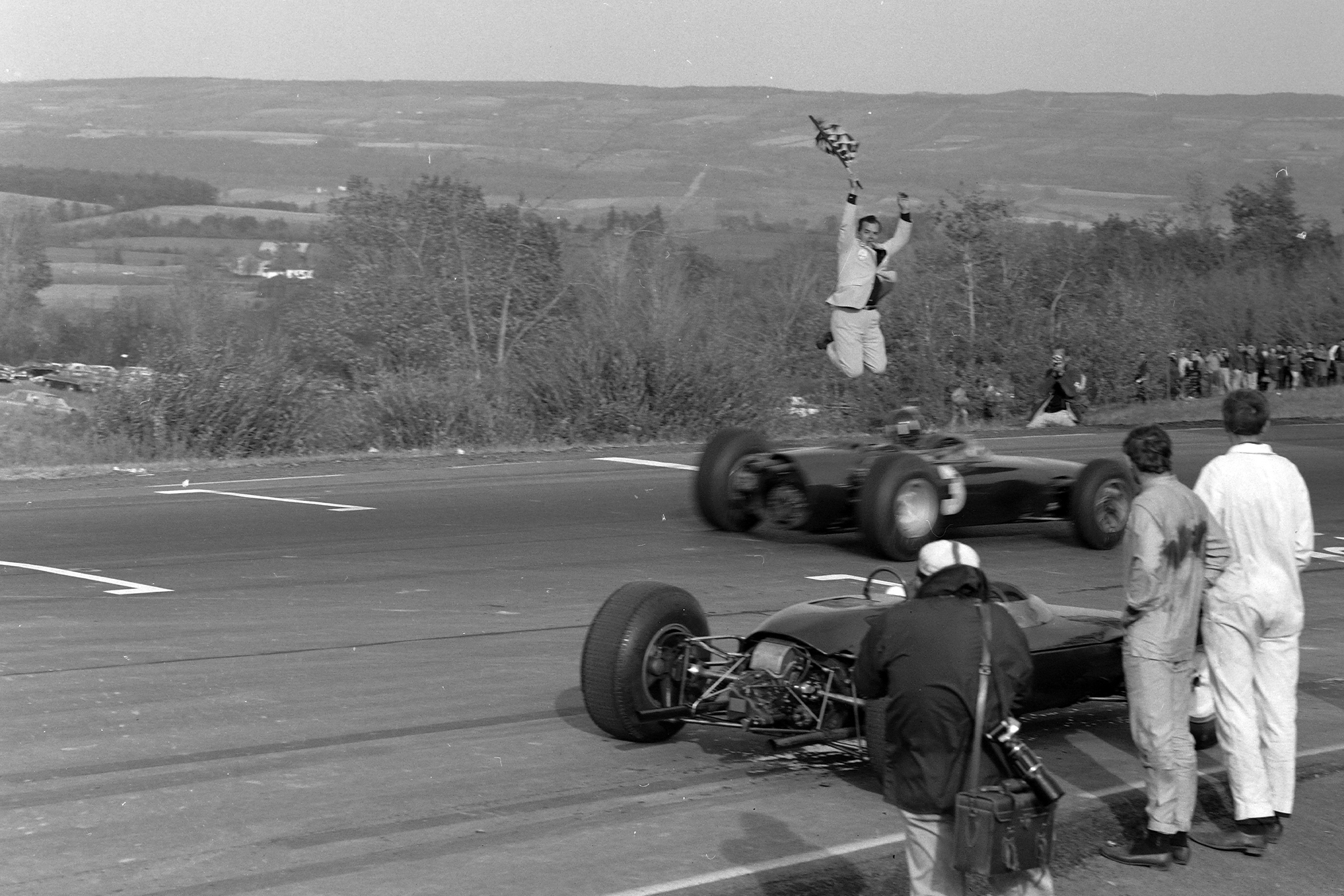 Graham Hill, BRM P261, crosses the finish line and takes the chequered flag.