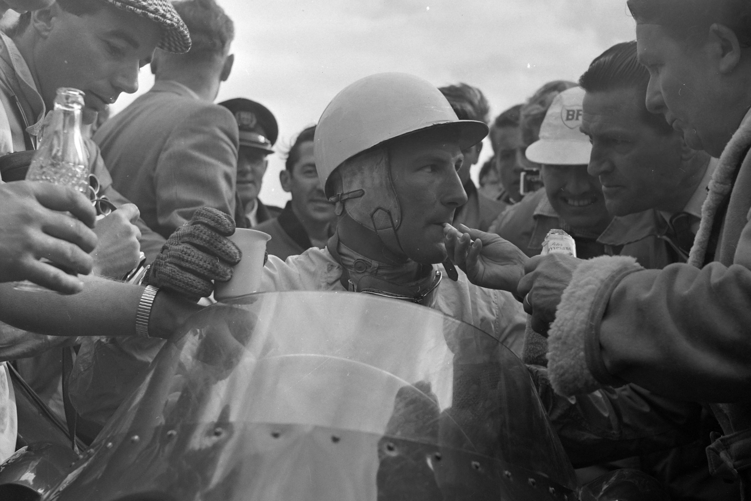 Stirling Moss is handed a cigarette and a drink following his victory.