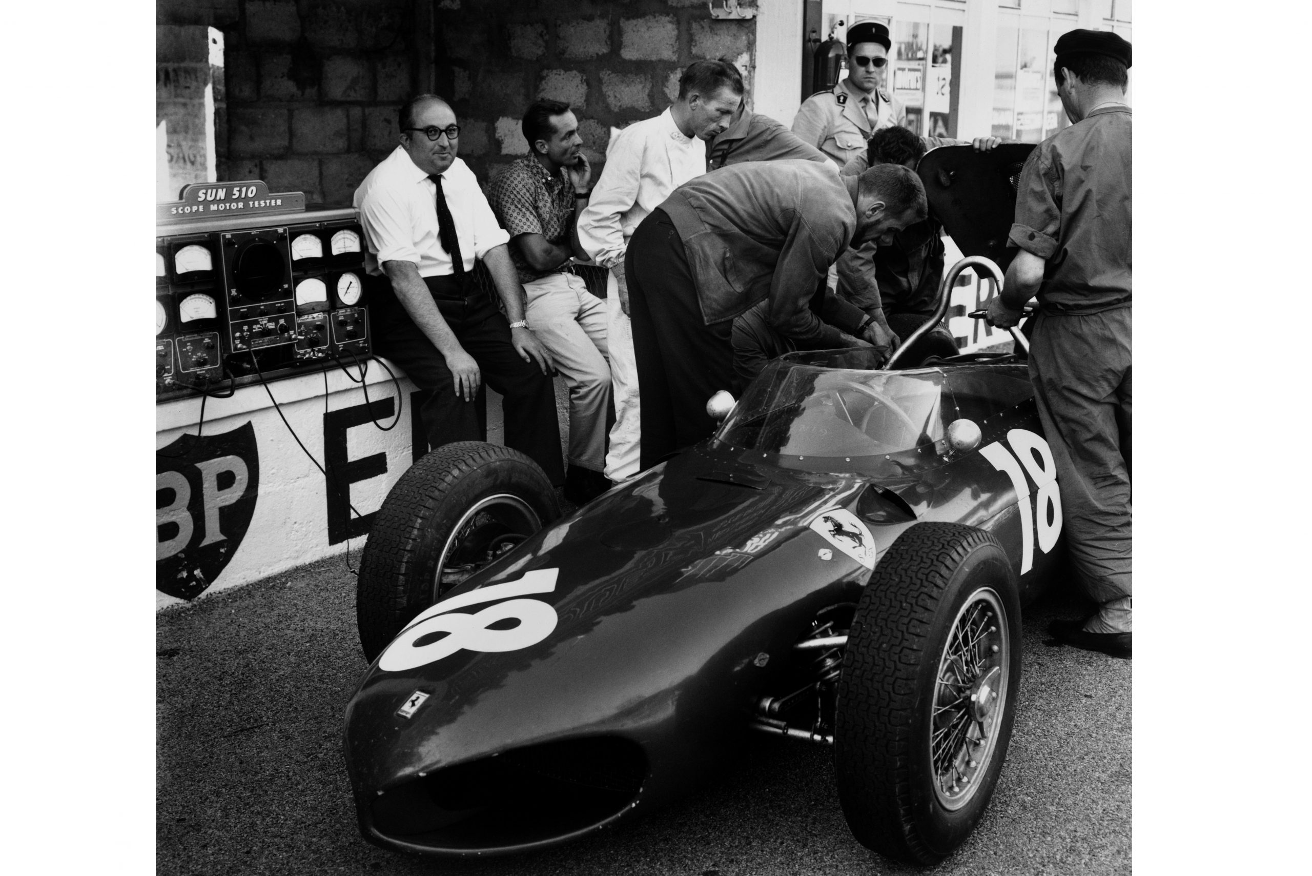 Carlo Chiti, Ferrari engine designer sitting on the pit wall with Phil Hill and Richie Ginther.
