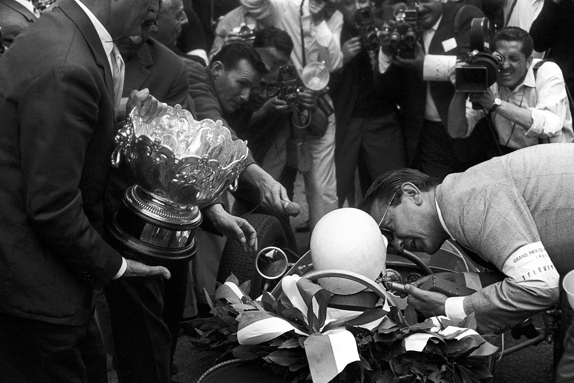 A reporter speaks to Stirling Moss in his Lotus after winning the 1961 Monaco Grand Prix