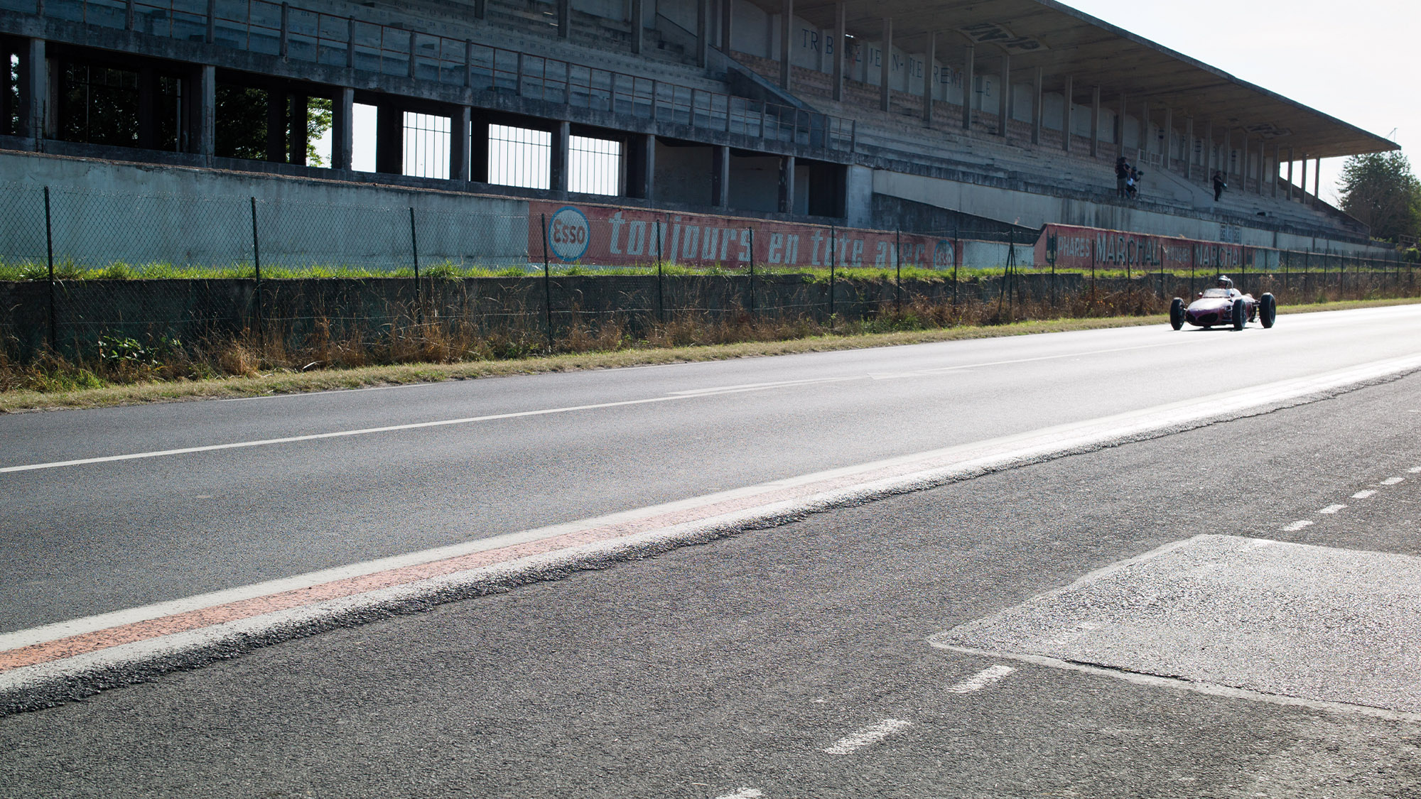 Derek Hill drives past the Reims box in the Sharknose Ferrari 156